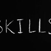 Chalkboard with the word ‘skills’ written, emphasizing essential coaching skills.