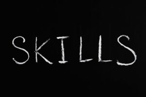 Chalkboard with the word ‘skills’ written, emphasizing essential coaching skills.