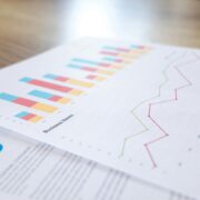Close-up of printed business reports showing colorful bar charts and line graphs with life coaching statistics and trends.