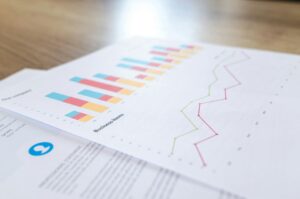 Close-up of printed business reports showing colorful bar charts and line graphs with life coaching statistics and trends.