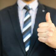 Close-up of a business professional giving a thumbs up, symbolizing confidence and success in career coaching