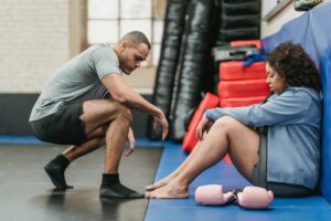 Health and wellness coach supporting a woman during a workout session, offering encouragement and mindset support in a gym setting.