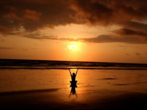 Person practicing meditation at sunrise on a beach, symbolizing inner peace and personal growth—an ideal representation of the journey through mindfulness certification.