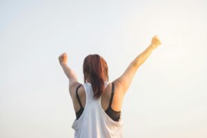 Client putting her arms up, feeling like a winner after a session with a mindful life coach.
